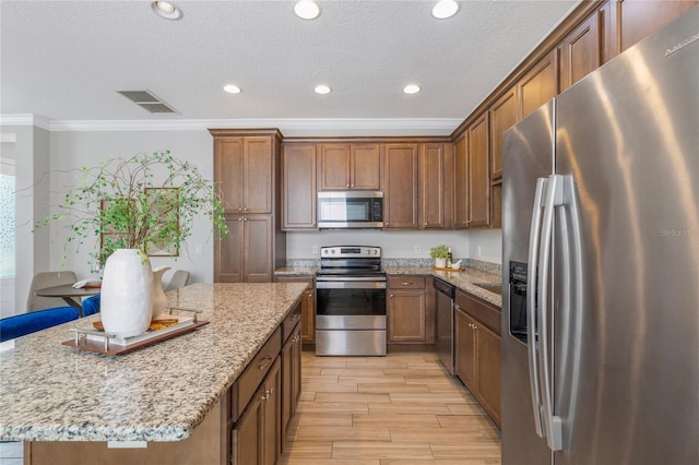 527 Jetstar Ln, Oldsmar, FL 34677 - kitchen featuring stainless steel appliances, ornamental molding, light wood finished floors, a kitchen island, and light stone counters