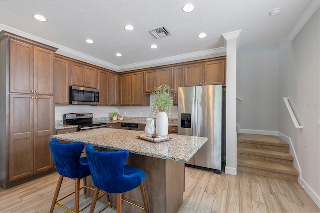 527 Jetstar Ln, Oldsmar, FL 34677 - kitchen featuring stainless steel appliances, a kitchen bar, a kitchen island, ornamental molding, and light stone countertops