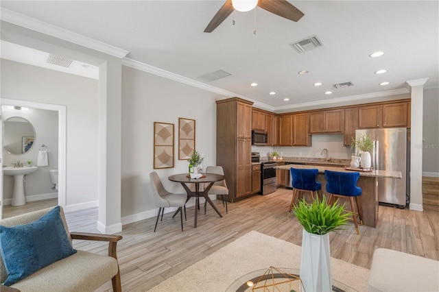 527 Jetstar Ln, Oldsmar, FL 34677 - kitchen with stainless steel appliances, recessed lighting, a kitchen island, light wood finished floors, and crown molding