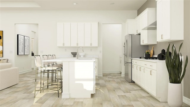 6913 116th Ct E, Palmetto, FL 34221 - kitchen featuring light wood finished floors, a breakfast bar area, light countertops, white cabinets, and a center island with sink