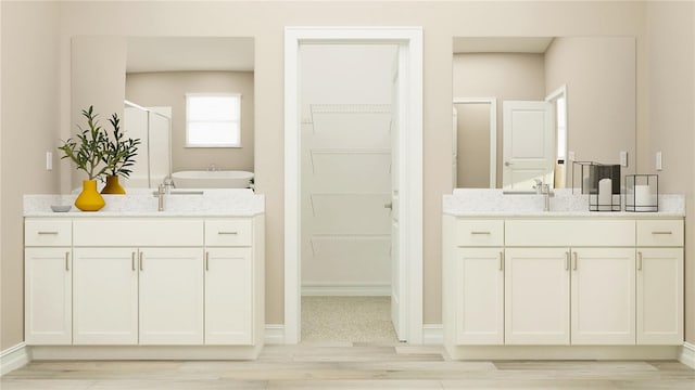 6913 116th Ct E, Palmetto, FL 34221 - full bathroom with a shower stall, a walk in closet, wood finished floors, and two vanities