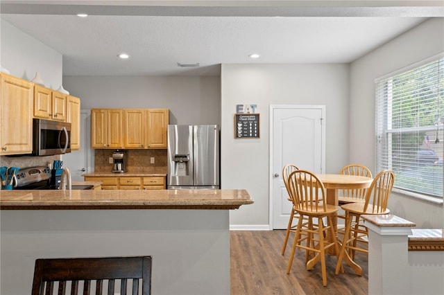 4715 Barnstead Dr, Riverview, FL 33578 - kitchen featuring appliances with stainless steel finishes, light brown cabinetry, wood finished floors, backsplash, and healthy amount of natural light