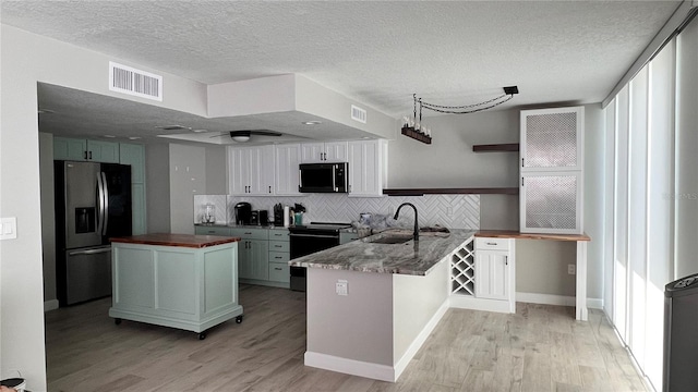17408 Gulf Blvd Unit 601, Redington Shores, FL 33708 - kitchen with appliances with stainless steel finishes, wood counters, a peninsula, light wood finished floors, and a textured ceiling