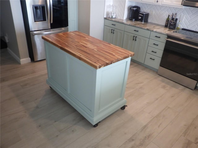 17408 Gulf Blvd Unit 601, Redington Shores, FL 33708 - kitchen with wooden counters, appliances with stainless steel finishes, light wood-type flooring, tasteful backsplash, and a kitchen island