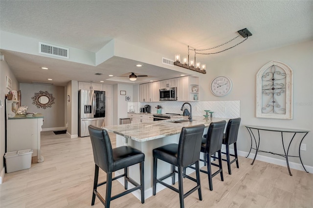 17408 Gulf Blvd Unit 601, Redington Shores, FL 33708 - kitchen featuring stainless steel appliances, a peninsula, light stone counters, a kitchen breakfast bar, and a textured ceiling