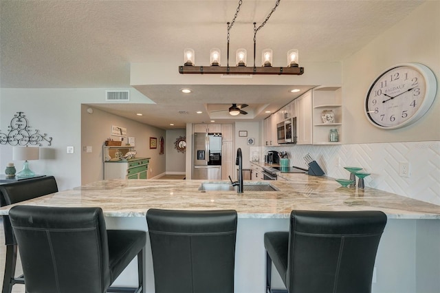 17408 Gulf Blvd Unit 601, Redington Shores, FL 33708 - kitchen featuring stainless steel appliances, a peninsula, tasteful backsplash, open shelves, and light stone counters