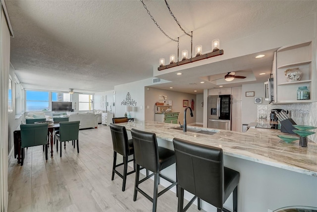 17408 Gulf Blvd Unit 601, Redington Shores, FL 33708 - kitchen with stainless steel fridge with ice dispenser, a peninsula, a textured ceiling, open shelves, and a ceiling fan