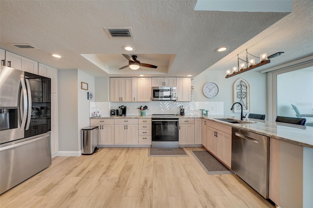 17408 Gulf Blvd Unit 601, Redington Shores, FL 33708 - kitchen featuring stainless steel appliances, a textured ceiling, a peninsula, light wood finished floors, and decorative backsplash