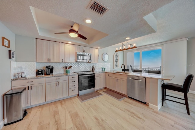 17408 Gulf Blvd Unit 601, Redington Shores, FL 33708 - kitchen with appliances with stainless steel finishes, a peninsula, a textured ceiling, decorative backsplash, and light wood-style flooring