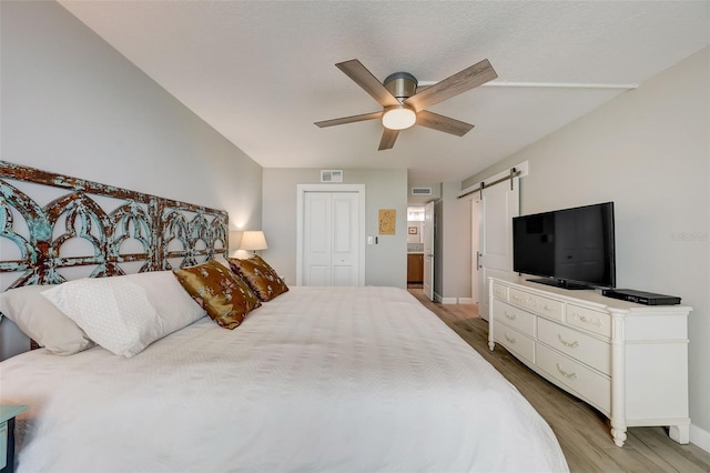 17408 Gulf Blvd Unit 601, Redington Shores, FL 33708 - bedroom with light wood-type flooring, a barn door, a closet, and ceiling fan