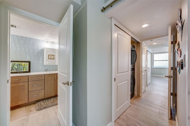 17408 Gulf Blvd Unit 601, Redington Shores, FL 33708 - hall with stacked washer and clothes dryer, light wood-type flooring, and recessed lighting