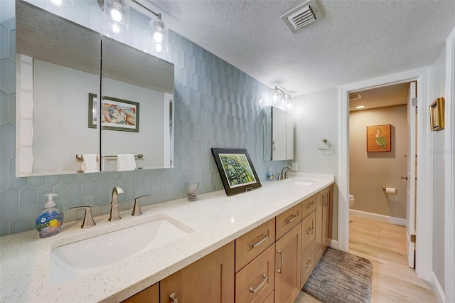 17408 Gulf Blvd Unit 601, Redington Shores, FL 33708 - full bathroom featuring double vanity, a textured ceiling, wood finished floors, and backsplash