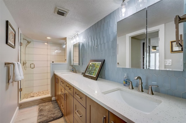 17408 Gulf Blvd Unit 601, Redington Shores, FL 33708 - bathroom featuring a textured ceiling, a shower stall, double vanity, and decorative backsplash