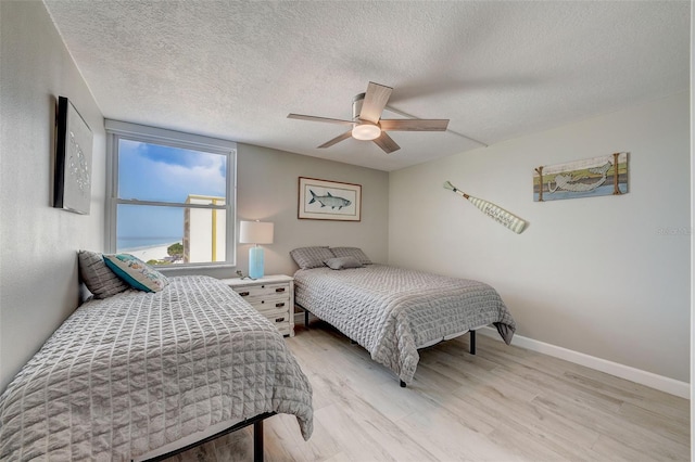 17408 Gulf Blvd Unit 601, Redington Shores, FL 33708 - bedroom featuring light wood-style floors, a textured ceiling, and a ceiling fan