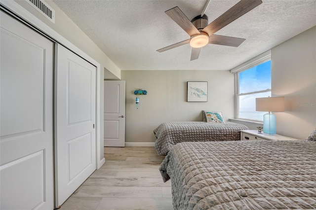 17408 Gulf Blvd Unit 601, Redington Shores, FL 33708 - bedroom with a textured ceiling, light wood-style floors, a closet, and ceiling fan