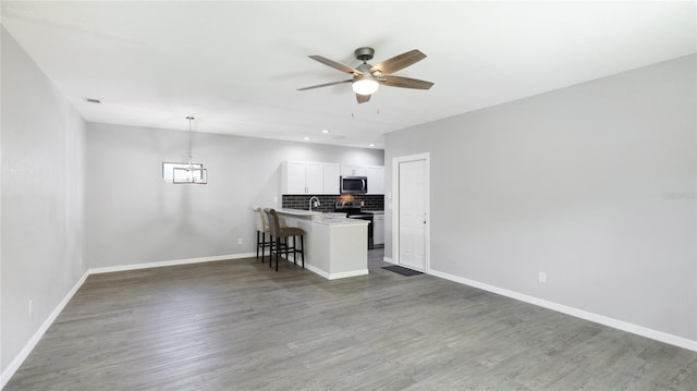 3051 27th Ct E, Palmetto, FL 34221 - kitchen with stainless steel microwave, a kitchen bar, ceiling fan, open floor plan, and recessed lighting