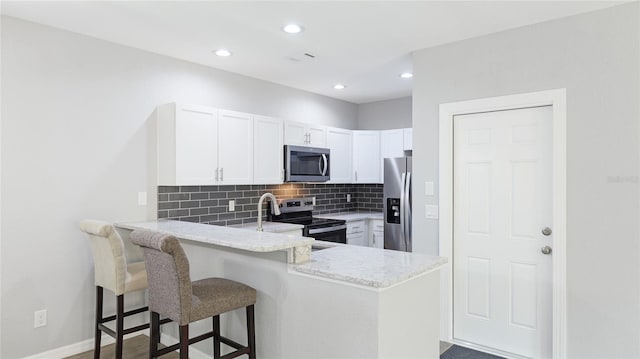 3051 27th Ct E, Palmetto, FL 34221 - kitchen with appliances with stainless steel finishes, a peninsula, decorative backsplash, light stone countertops, and white cabinets