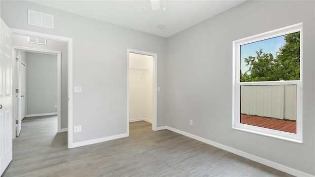 3051 27th Ct E, Palmetto, FL 34221 - unfurnished bedroom featuring light wood-style flooring, a walk in closet, and a closet