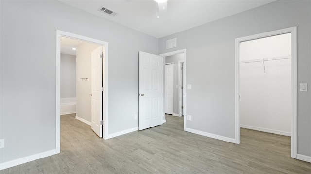 3051 27th Ct E, Palmetto, FL 34221 - unfurnished bedroom featuring wood finished floors, a spacious closet, a closet, and connected bathroom