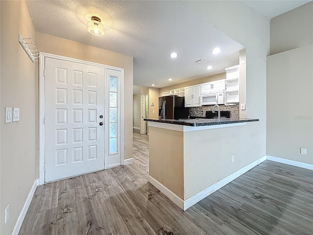 1741 Oak Spring Dr, Tarpon Springs, FL 34689 - kitchen featuring white microwave, refrigerator with ice dispenser, wood finished floors, dark countertops, and white cabinetry