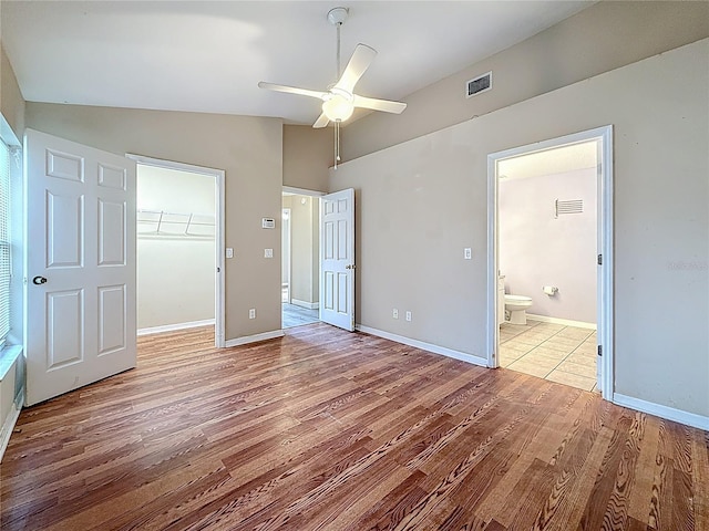 1741 Oak Spring Dr, Tarpon Springs, FL 34689 - unfurnished bedroom featuring vaulted ceiling, wood finished floors, a closet, a spacious closet, and connected bathroom