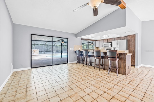 10430 Bobcat Dr, New Port Richey, FL 34654 - kitchen featuring stainless steel microwave, fridge with ice dispenser, a ceiling fan, a kitchen breakfast bar, and a peninsula