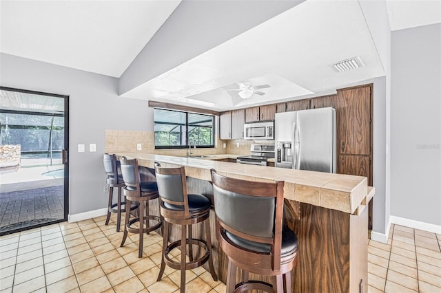 10430 Bobcat Dr, New Port Richey, FL 34654 - kitchen with stainless steel appliances, a peninsula, a breakfast bar, and backsplash