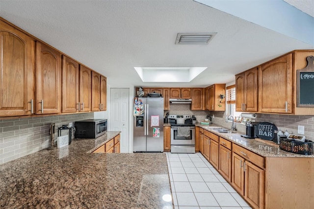 6101 Broken Arrow Dr, New Port Richey, FL 34653 - kitchen featuring stainless steel appliances, brown cabinets, under cabinet range hood, backsplash, and stone counters