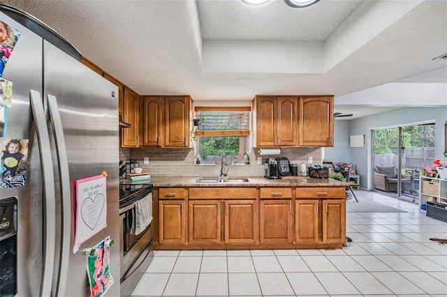 6101 Broken Arrow Dr, New Port Richey, FL 34653 - kitchen featuring stainless steel appliances, brown cabinets, backsplash, a tray ceiling, and light stone counters