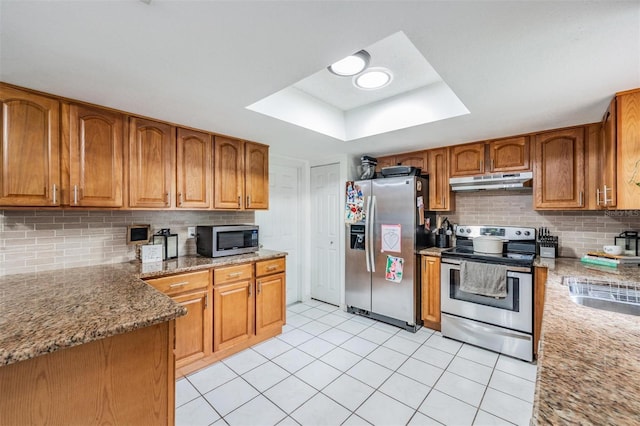 6101 Broken Arrow Dr, New Port Richey, FL 34653 - kitchen featuring stainless steel appliances, under cabinet range hood, tasteful backsplash, brown cabinetry, and light tile patterned floors