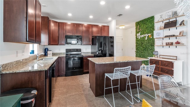 14317 Italia Dr, Wimauma, FL 33598 - kitchen featuring black appliances, a center island, a kitchen bar, light stone counters, and recessed lighting