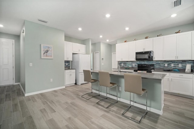 11829 Brighton Knoll Loop, Riverview, FL 33579 - kitchen with black appliances, decorative backsplash, light wood-type flooring, a center island with sink, and recessed lighting