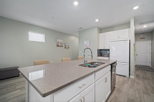 11829 Brighton Knoll Loop, Riverview, FL 33579 - kitchen featuring freestanding refrigerator, light wood-type flooring, light stone counters, a center island with sink, and white cabinetry