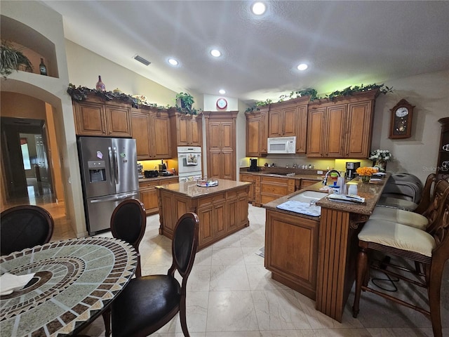 6900 Molakai Cir, Boynton Beach, FL 33437 - kitchen with white appliances, brown cabinetry, recessed lighting, a peninsula, and light marble finish floors