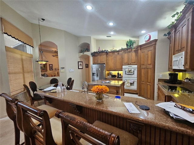 6900 Molakai Cir, Boynton Beach, FL 33437 - kitchen with white appliances, arched walkways, a kitchen breakfast bar, stone countertops, and brown cabinetry