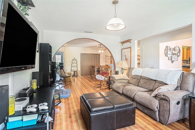 750 Caliente Dr, Brandon, FL 33511 - living area with light wood-style flooring, arched walkways, a ceiling fan, and a textured ceiling
