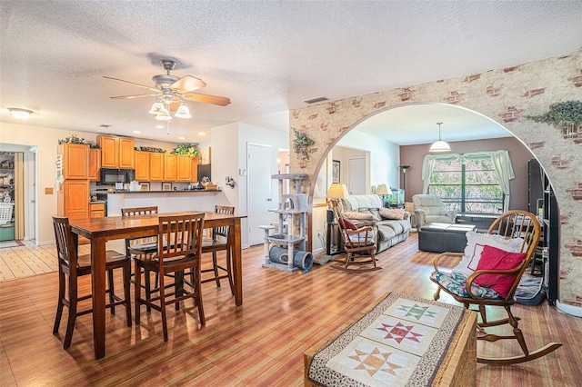 750 Caliente Dr, Brandon, FL 33511 - dining area featuring arched walkways, light wood-type flooring, ceiling fan, a textured ceiling, and wallpapered walls