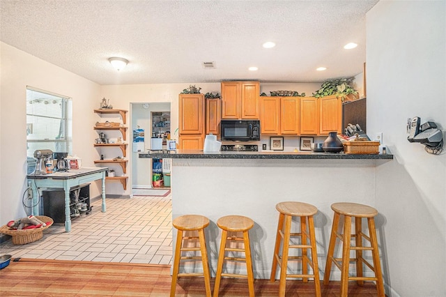 750 Caliente Dr, Brandon, FL 33511 - kitchen with black microwave, a kitchen bar, a peninsula, recessed lighting, and dark countertops