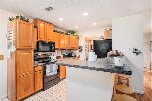 750 Caliente Dr, Brandon, FL 33511 - kitchen featuring black appliances, a kitchen bar, a peninsula, dark countertops, and recessed lighting