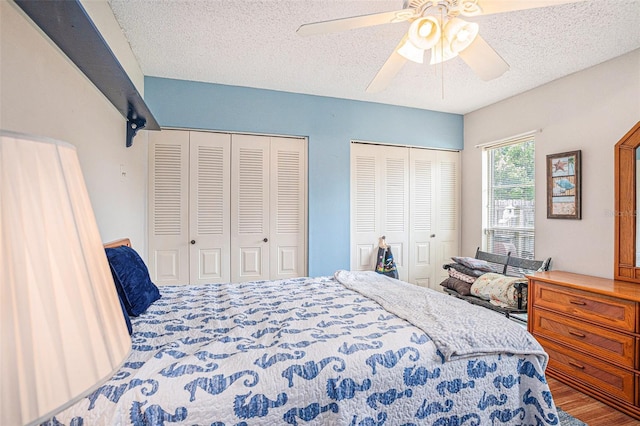 750 Caliente Dr, Brandon, FL 33511 - bedroom featuring two closets, a textured ceiling, a ceiling fan, and wood finished floors