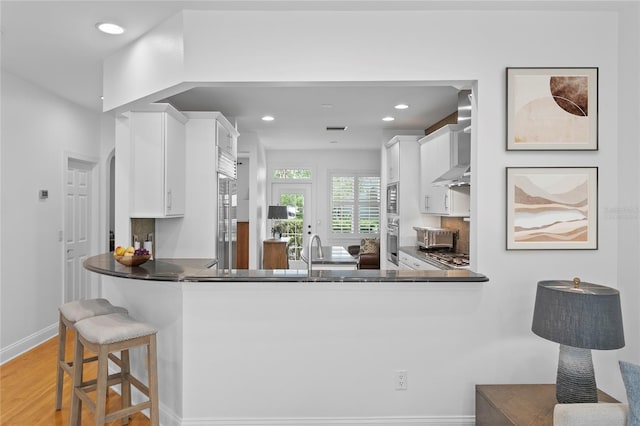 305 Sea Island Way, Tampa, FL 33602 - kitchen with oven, white cabinets, recessed lighting, wall chimney range hood, and dark countertops
