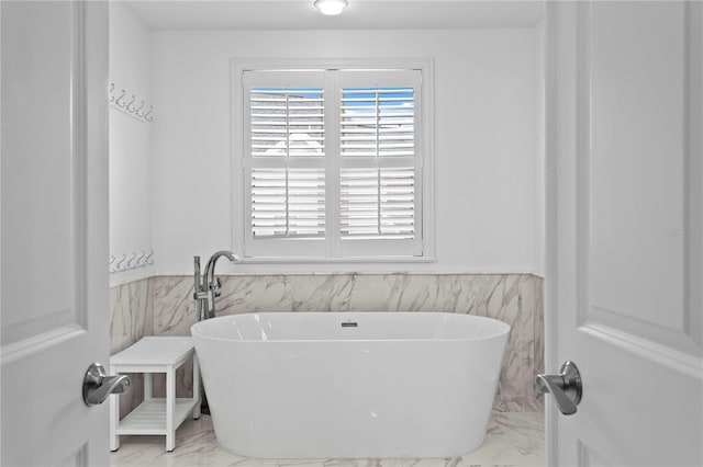 305 Sea Island Way, Tampa, FL 33602 - bathroom with marble look tiles, a wainscoted wall, a freestanding bath, and tile walls