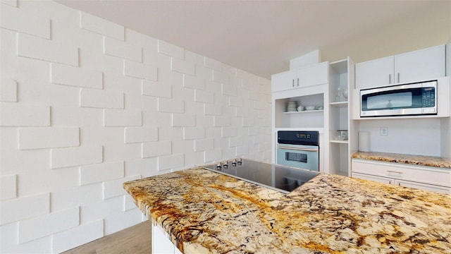 1431 Island Dr S, South Pasadena, FL 33707 - kitchen featuring stainless steel appliances, open shelves, white cabinetry, light stone counters, and wood finished floors