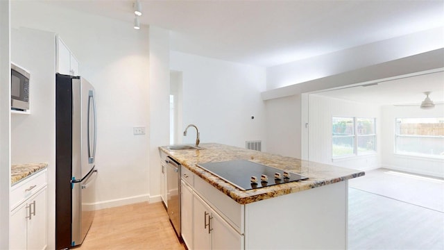 1431 Island Dr S, South Pasadena, FL 33707 - kitchen with appliances with stainless steel finishes, light wood-style floors, a peninsula, light stone counters, and white cabinets