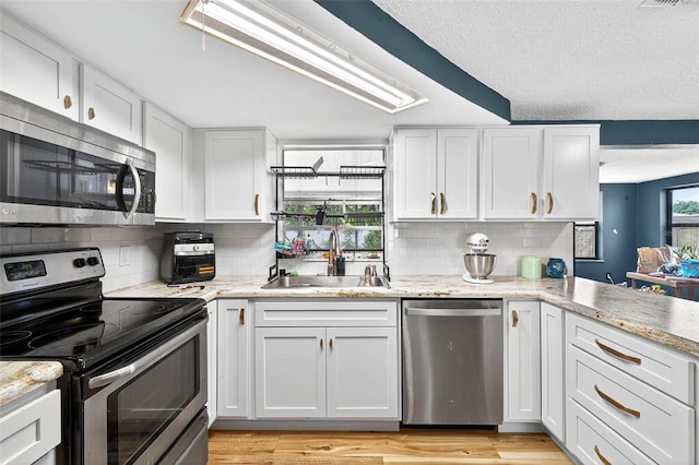 7814 Burnham Dr, Port Richey, FL 34668 - kitchen with stainless steel appliances, decorative backsplash, white cabinetry, light stone counters, and a textured ceiling