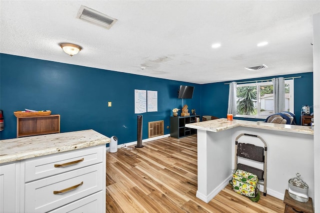7814 Burnham Dr, Port Richey, FL 34668 - kitchen featuring white cabinetry, light wood-style floors, light stone counters, recessed lighting, and a textured ceiling