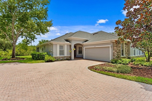 27455 Mistflower Dr, Wesley Chapel, FL 33544 - ranch-style house with stone siding, a garage, stucco siding, decorative driveway, and a shingled roof