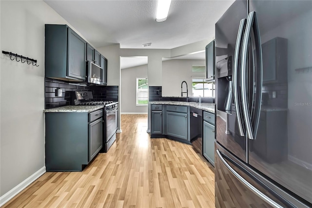 19635 Bellehurst Loop, Land O Lakes, FL 34638 - kitchen with appliances with stainless steel finishes, light wood finished floors, tasteful backsplash, and light stone counters