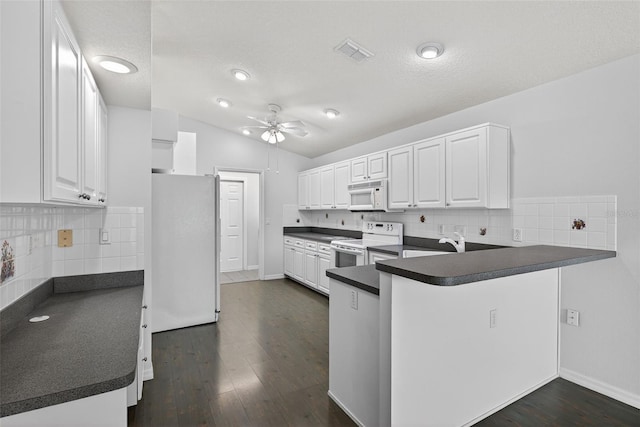 11348 Tee Time Cir, New Port Richey, FL 34654 - kitchen featuring white appliances, dark countertops, a peninsula, a ceiling fan, and white cabinets
