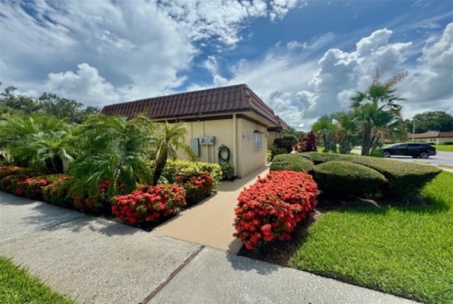 1701 Pinehurst Rd Unit 24B, Dunedin, FL 34698 - view of property exterior featuring stucco siding, a tiled roof, and a lawn